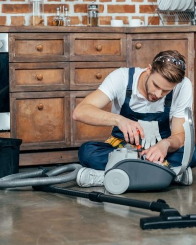 professional repairman fixing vacuum cleaner